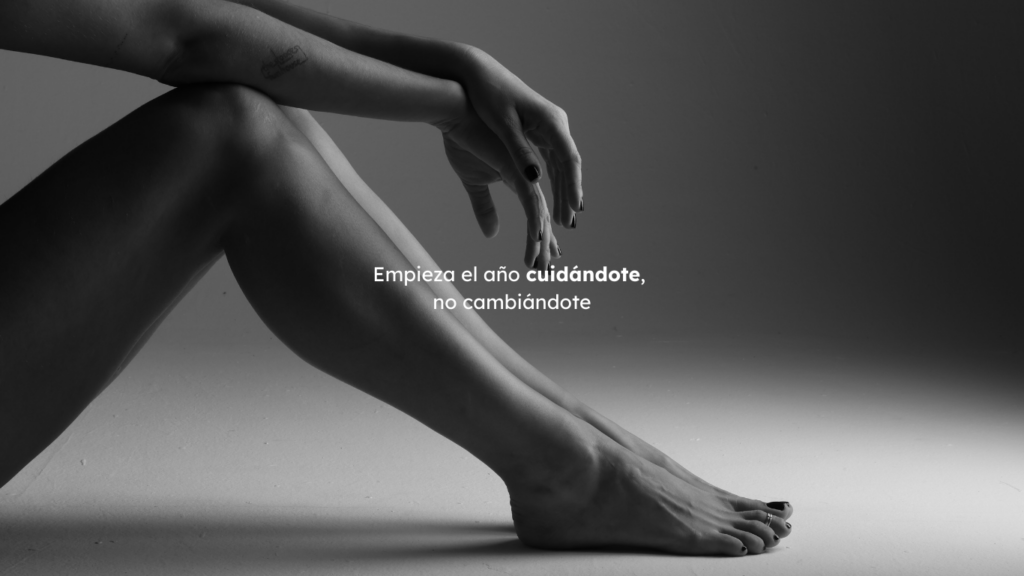 Piernas y brazos desnudos en blanco y negro con el mensaje “Empieza el año cuidándote, no cambiándote”, invitando a Regala masaje Madrid.