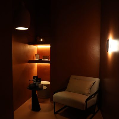 Rincón de descanso con sillón claro, mesa de té y estanterías iluminadas en un espacio cálido, preparado para Regala masaje Madrid.