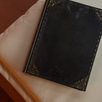 Cuaderno de tapas negras con detalles dorados apoyado sobre una camilla, evocando un espacio íntimo para Regala masaje Madrid.